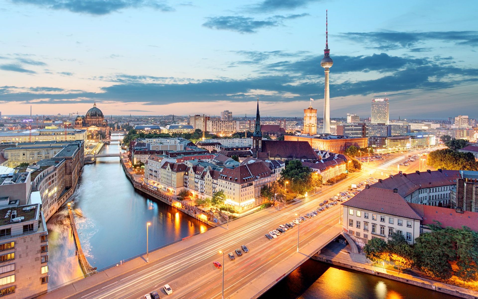 Ein Panoramablick über Berlin in einer warmen Abendstimmung. Unter anderem zu sehen: Reichstaggebäude, die Spree, Alexanderplatz