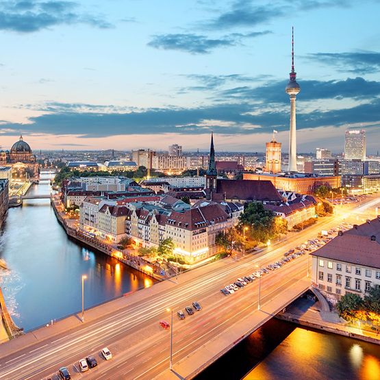 Ein Panoramablick über Berlin in einer warmen Abendstimmung. Unter anderem zu sehen: Reichstaggebäude, die Spree, Alexanderplatz