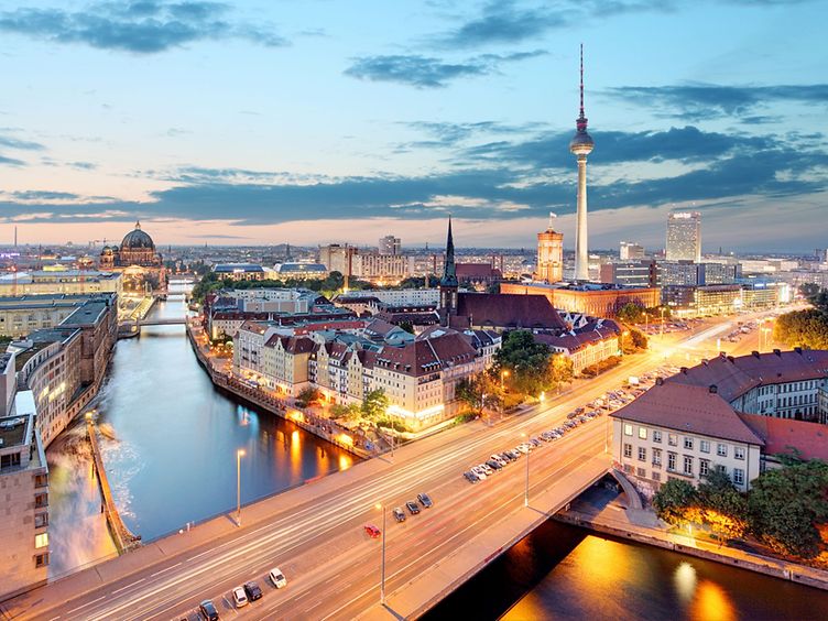 Ein Panoramablick über Berlin in einer warmen Abendstimmung. Unter anderem zu sehen: Reichstaggebäude, die Spree, Alexanderplatz